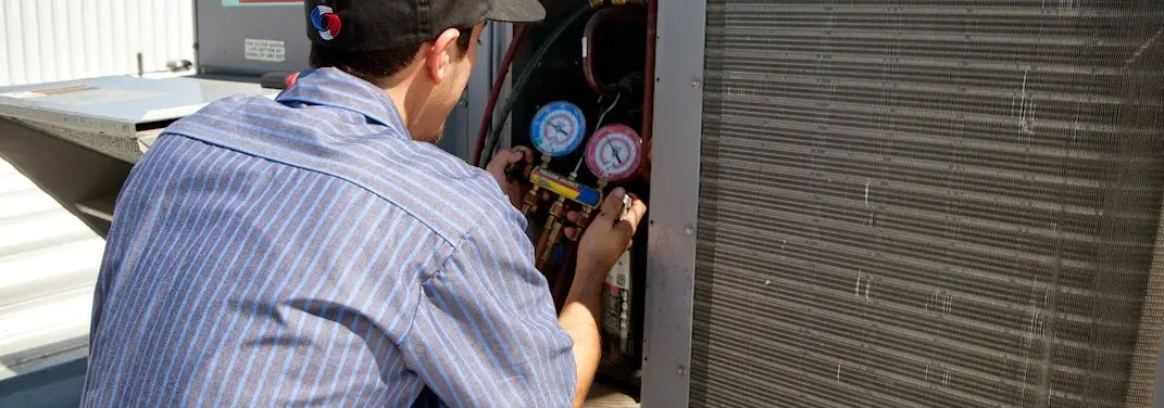 HVAC technician servicing a condenser unit in Franklin